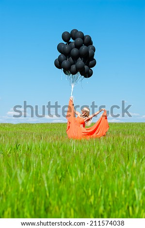 elegant woman in orange dress with black balloons