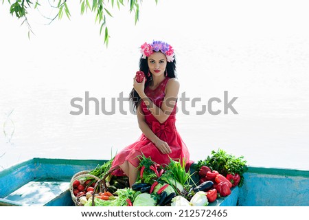 beautiful woman on the boat with vegetables holding pepper in hand