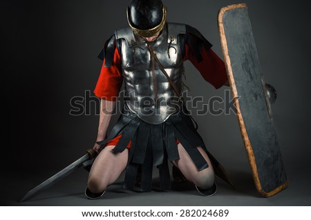 tired soldier kneeling with a shield and a sword in hands