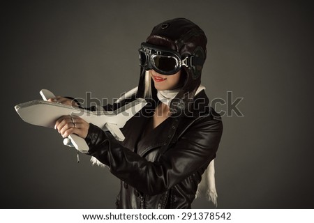woman in aviator hat standing with toy airplane
