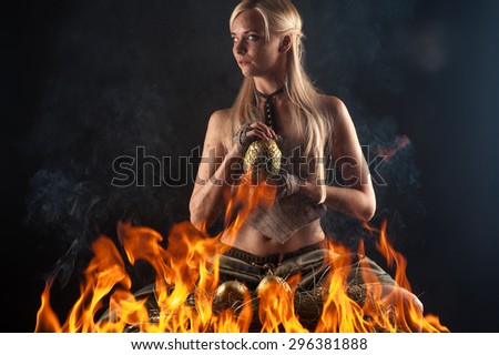 beautiful blond with a dragon egg in hands in the fire