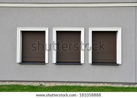 Outdoor three window blinds closed on grey wall