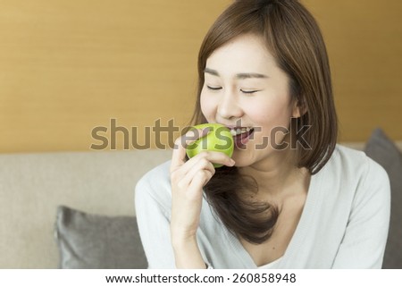 Young woman relaxing at home eating apple