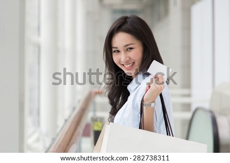 Asian woman holding shopping bags and a card