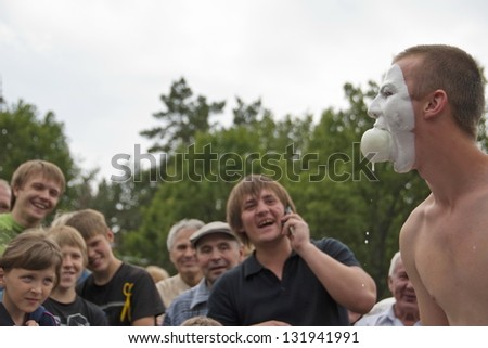 VORONEZH, RUSSIA - JULY 5: Unidentified man takes part in a funny contest at festival Sabantuy, July 5, 2009 in Voronezh, Russia. Winner must take apple from bowl with milk without using his hands.