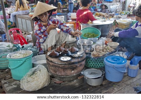 MUI NE, VIETNAM - NOVEMBER 3: Unidentified vietnamese woman in conical hat cooks traditional pancakes in market of Mui Ne, Vietnam on November 3, 2008. Street food is very popular in Vietnam.