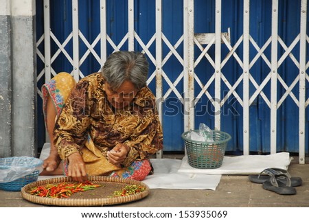 KANCHANABURI, THAILAND - NOVEMBER 19: Unidentified elderly Thai woman sort a chili pepper out on a street on November 19, 2008 in Kanchanaburi, Thailand. Street selling is main source money for her.