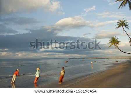 MUI NE, VIETNAM - NOVEMBER 4: Unidentified Vietnamese people pull their seine out on the beach in Mui Ne, Vietnam on November 4, 2008. For most of Vietnamese seafood is main source of livelihood.