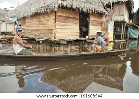 IQUITOS, PERU - APRIL 29: Unidentified Peruvian men in traditional boat float on water street in Belen, Iquitos, Peru on April 29, 2010. Boats are only mode of transport in the poor area of Iquitos.