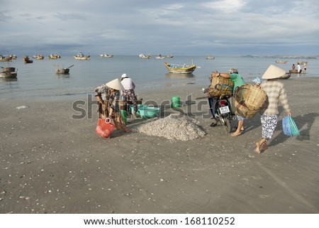 MUI NE, VIETNAM - NOVEMBER 3: Unidentified Vietnamese women carry new catch from fishing boats in Mui Ne, Vietnam on November 3, 2008. For most of Vietnamese seafood is main source of livelihood.