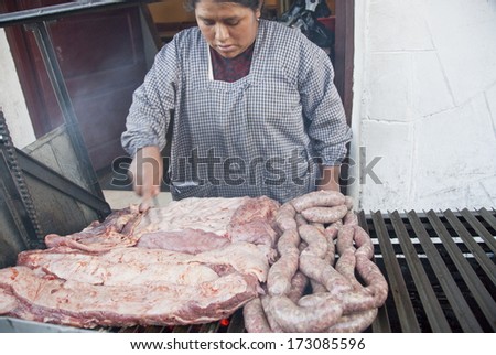 LA PAZ, BOLIVIA - MAY 8: Unidentified Bolivian woman cooks traditional grilled pork on a street in La Paz, Bolivia on May 8, 2010. Family street restaurants are common for Bolivian cities.