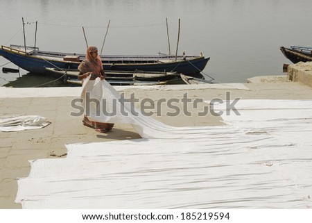 VARANASI, INDIA - APRIL 30: Unidentified Indian woman lays out clothes for drying on Ganges\'s bank, April 30, 2009 in Varanasi, India. For most Indian women heavy manual labor is a common practice.