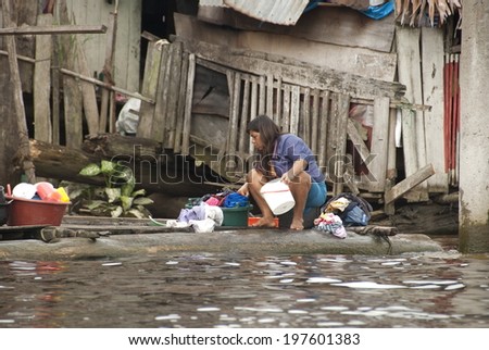 IQUITOS, PERU - APRIL 29: Unidentified woman washes clothes on a water street of Belen on April 29, 2010, Iquitos, Peru. Belen is the biggest slum in Peru and women\'s labor is a common practice here.