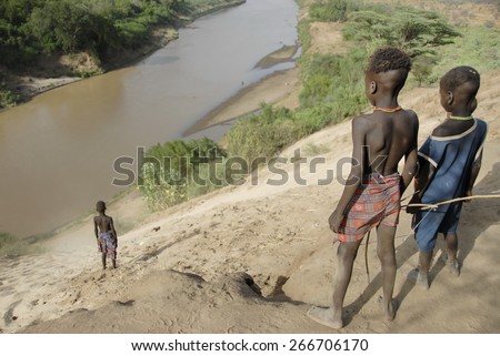 OMO VALLEY, ETHIOPIA - MARCH 15: Unidentified Karo kids down to the river to bathe, Colcho, Omo Valley, Ethiopia on March 15, 2012. The Omo River is essential for local tribes and their livestock.