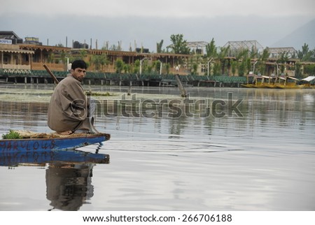 SRINAGAR, INDIA - MAY 6: Unidentified Kashmiri man goes fishing in the Dal Lake with living houseboats in the background, Srinagar, India, May 6, 2009. Dal Lake is important source of livelihood.