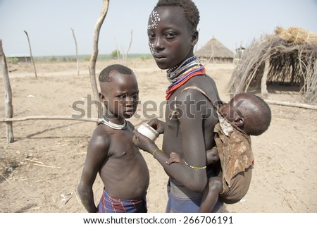 COLCHO, ETHIOPIA - MARCH 16: Unidentified Karo kids put on a makeup before visit of tourists, March 16, 2012, Omo Valley, Ethiopia. According guidebooks Karo is the most decorated tribe in Omo Valley.