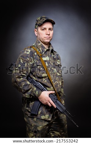 Man in military uniform standing with a gun