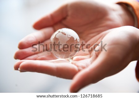Human hand and a transparent glass earth