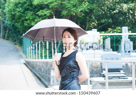 Lady with black clothes to worship at the grave with a parasol
