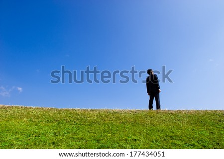 Suits men looking up at the blue sky while standing in grassland