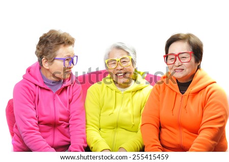 Three elderly women of fun smile wearing colorful clothes and glasses