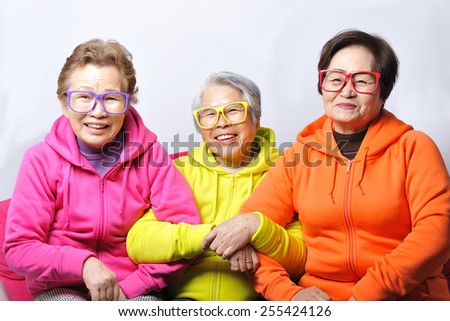 Three elderly women of fun smile wearing colorful clothes and glasses