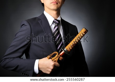 Male businessman wearing a suit to have the sword of Japanese samurai