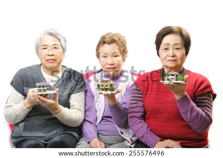 Three elderly women that have a model of the house