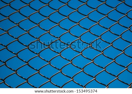Metal mesh wire fence with blue sky background