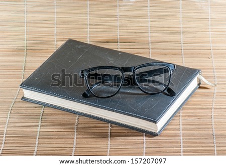Book and glasses on bamboo background