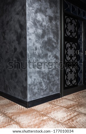 Corner Wall With Textured Venetian Plaster In The Interior With Black Door