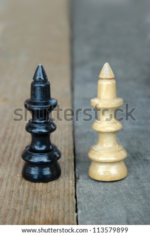 conceptual photo of similarity and difference with old chess queen figures on a contrast wooden background. This contrast concept with same figures can represent a lot of things (as key words...)