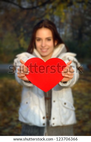 woman out of focus holding paper heart. Focus on heart. Heart is flat, convenient for text