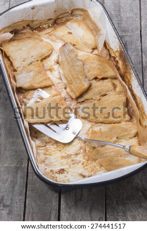 roasted catfish fillets in baking pan on baking paper with serving spoon