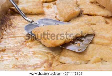 roasted catfish fillets in baking pan on baking paper with serving spoon
