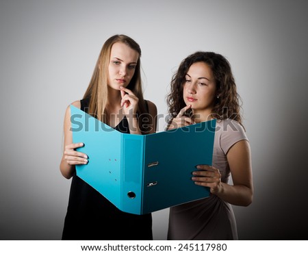 Two young female students are reading textbook. Young women are doing something.