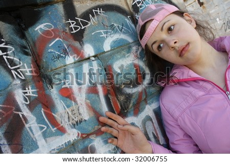 Beautiful sad girl near wall with graffiti