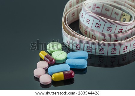 Weight management conceptual - pills and measuring tape.