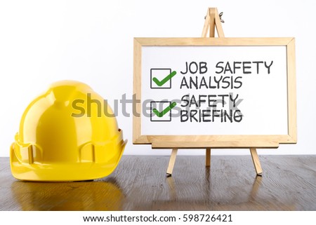 Safety helmet and white board with words Jon Safety Analysis & Safety Briefing,Health and Safety concept.