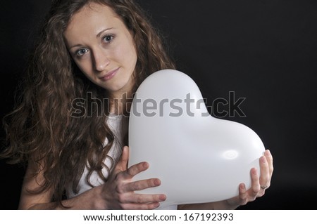 Young girl hugging a balloon as a heart