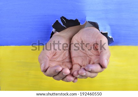 begging hands through Ukrainian flag