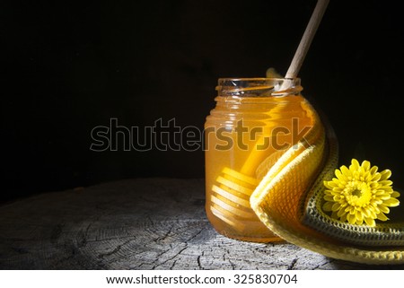 jar of honey and stick to honey on a wooden background