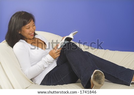 girl reading book on couch over blue background