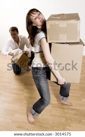 couple moving in apartment - woman carrying all boxes
