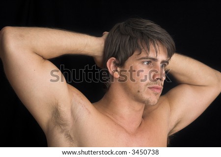 portrait of young man standing with no shirt on over black background