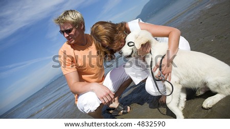 young couple petting dog on the beach vancouver