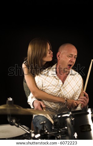 shot of woman bugging drummer playing over black backdrop