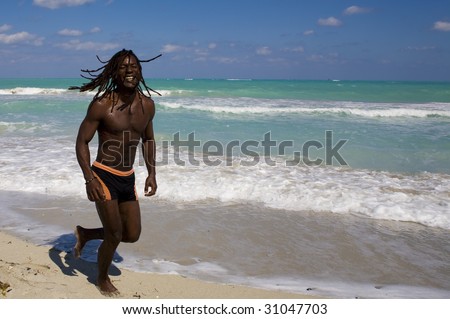 smiling black man running on the beach over blue sea and blue sky