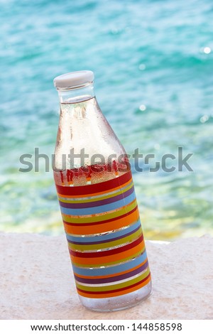 Bottle of fresh water by the sea. Water in glass bottle