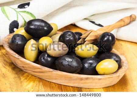 Olives in olive wood bowl with olive picker